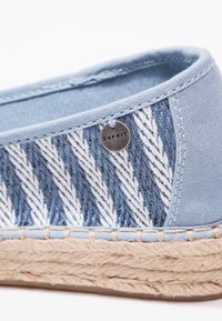 Espadrille bleu clair avec un motif chevron tissé blanc et bleu et une semelle en jute, dotée d'une petite étiquette ronde en métal de la marque Esprit.