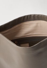 Interior de bolso de cuero marrón, con una textura suave, forro beige y un bolsillo con cremallera con detalles en dorado.