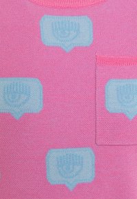 Pull rose en tricot texturé, avec des motifs de bulles de dialogue bleues et une petite poche avant. Encolure ronde et bords côtelés.