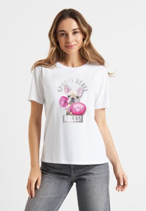 Vrouw draagt wit t-shirt met een Franse bulldog met roze bokshandschoenen en tekst "Sport is rebel," "Liefde" en "Regels!"