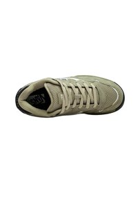 Zapatilla atlética color beige con parte superior de malla, puntera redonda, lengua acolchada y cordones planos. Suela de goma negra con sutiles acentos blancos.