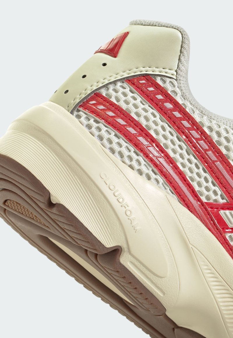 Sneaker grigio chiaro con accenti rossi. parte superiore in mesh, forma arrotondata, suola cloudfoam e suola in gomma testurizzata per la presa.