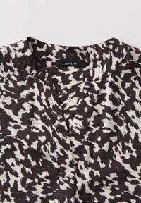 Jacquard-Oberteil in Schwarz und Creme mit einem abstrakten Muster, mit V-Ausschnitt und Etikett mit der Aufschrift "OPUS". Weicher, leichter Stoff.
