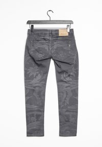 Jeans gris con patrón, que presentan un diseño floral, dos bolsillos traseros y una etiqueta de cuero en la cinturilla. Corte ajustado con una textura suave.