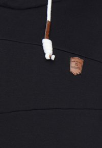 Felpa nera con design strutturato, coulisse bianca con fermo in legno e patch logo in pelle marrone.