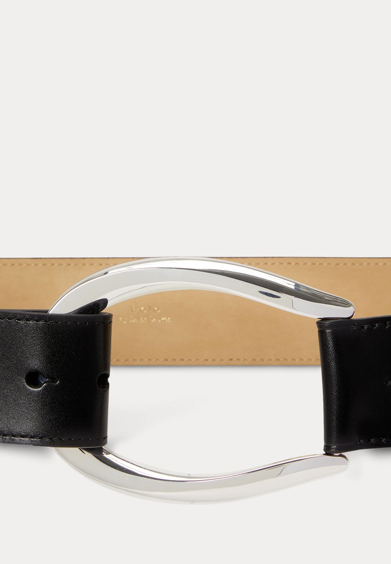 Ceinture en cuir noir avec une boucle en métal argenté lisse et courbe et un fond de ceinture beige.