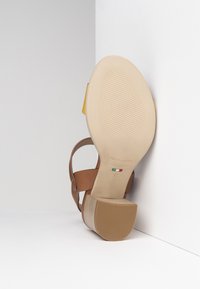 Sandalia de tacón alto de cuero marrón con una suela beige texturizada, que presenta una correa ancha y un acento amarillo. Talla 37, fabricada en Italia.