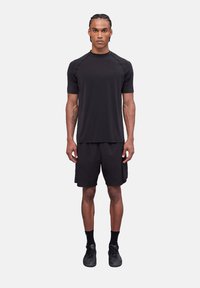 Conjunto deportivo negro que incluye una camiseta de manga corta y pantalones cortos. Fabricado con un tejido ligero de textura suave y un diseño ajustado.