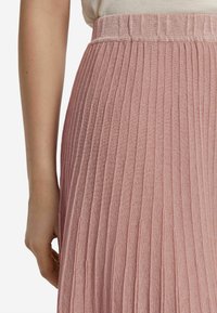 Plisserad midikjol i mjuk rosa tyg. Elastisk midja och vertikal texturdetalj, med en lätt glänsande finish.