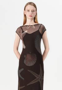 Svart kjole med sheer cap-sleeve-design, dekorert med fargerike marine liv-mønstre, inkludert skjell og sjøstjerner. Glatt tekstur.