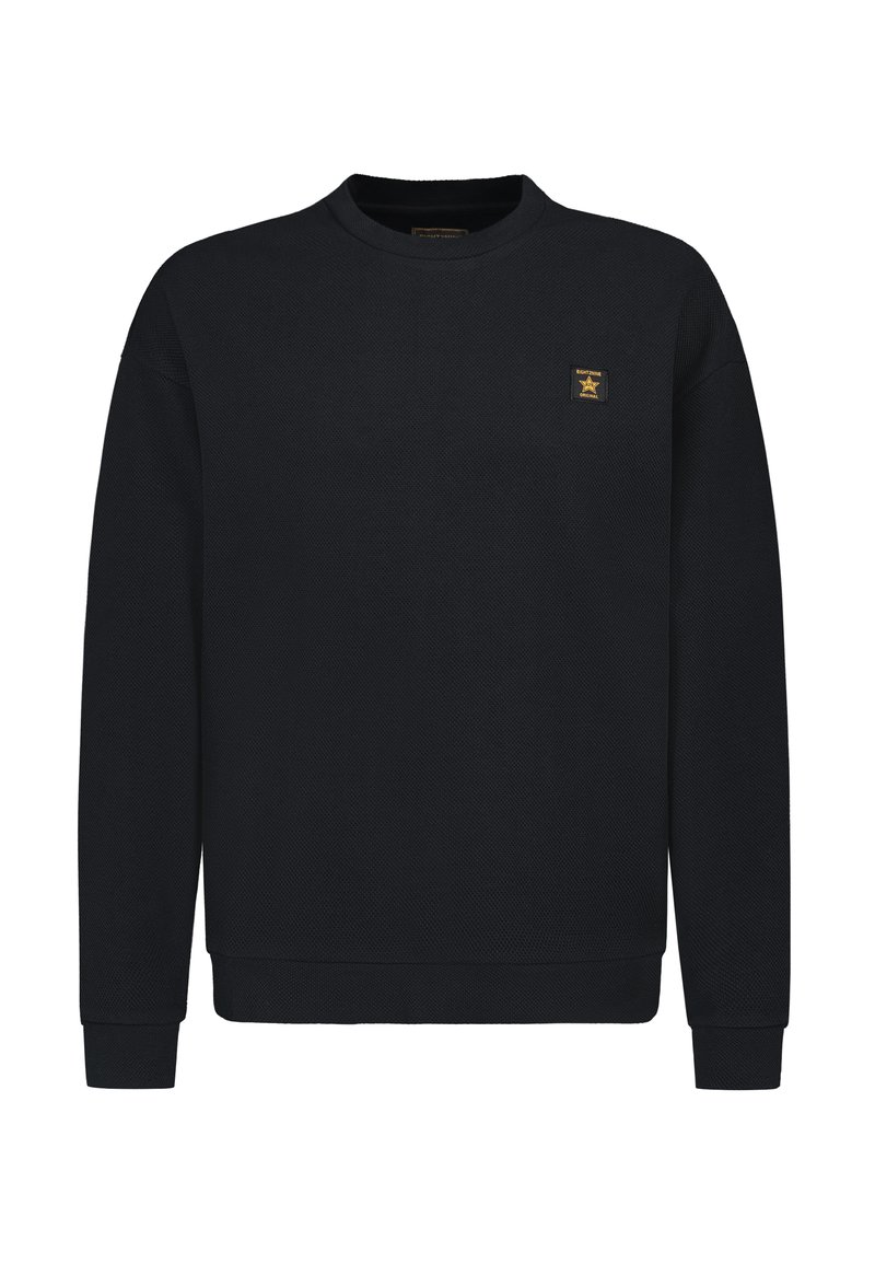 Black sweatshirt made of textured fabric, featuring a round neck, long sleeves, and a small gold logo patch on the left chest.