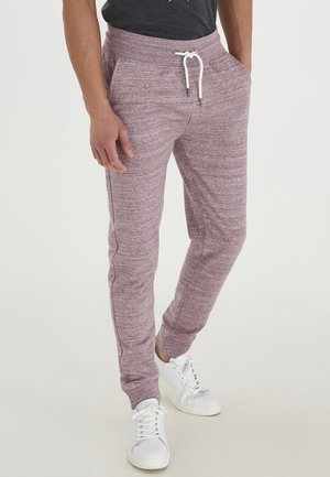 Maroon jogger pants with a textured knit finish, featuring a drawstring waistband and side pockets, paired with white sneakers.