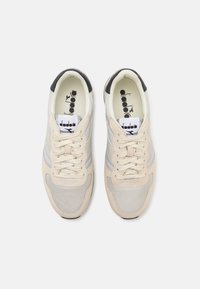Sneakers with a mesh and suede upper in shades of beige and gray, featuring a black heel cap and cream laces. Logo on the tongue.