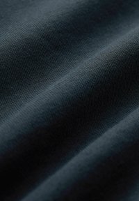 Tejido de punto azul oscuro con una textura suave, con un sutil patrón acanalado y una caída suave, mostrando múltiples pliegues.