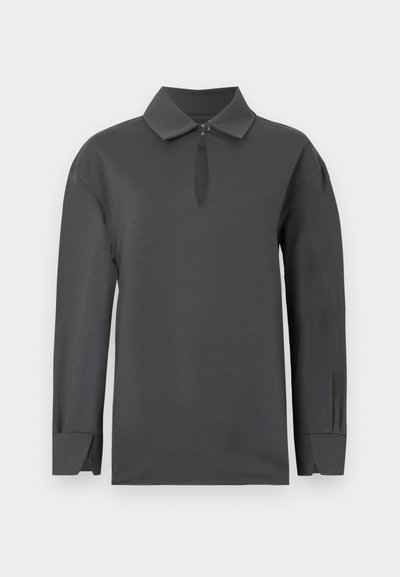 Μακρυμάνικο σκούρο γκρι πουκάμισο με μυτερό γιακά, άνοιγμα σε σχήμα κλειδιού κάτω από τον γιακά που κλείνει με κουμπί και φαρδιές μανσέτες με σχισμές.