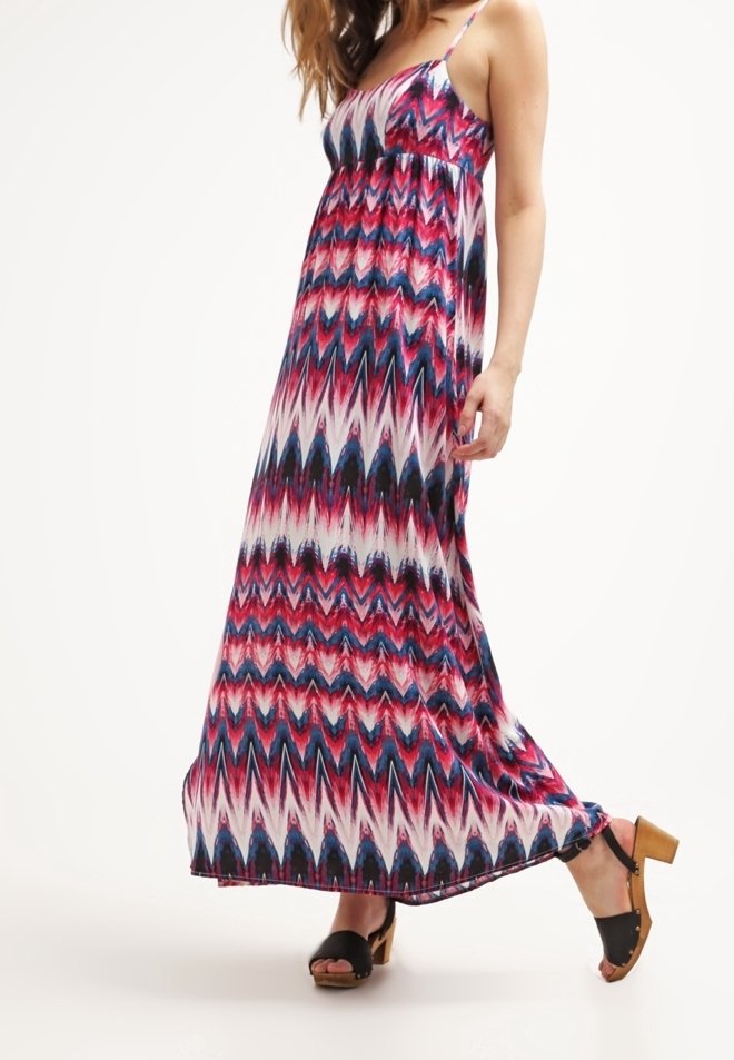 Robe maxi à motif zigzag rose, bleu et blanc. Fabriquée en tissu léger avec des bretelles fines et une coupe ample. Associée à des sandales noires.