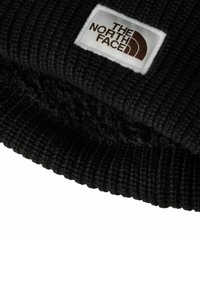 Berretto nero lavorato a maglia con texture a coste e risvolto. Presenta un'etichetta bianca con il logo "THE NORTH FACE" in marrone.