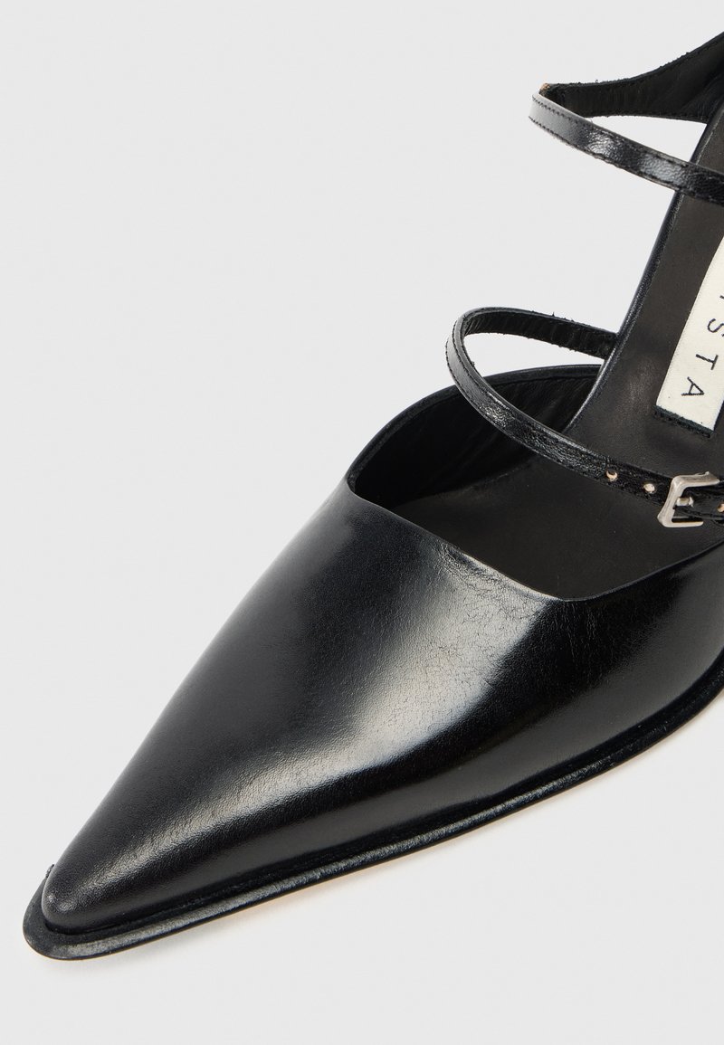 Black leather pointed-toe shoe with thin ankle straps and a sleek design. Smooth texture and minimalistic hardware accents.