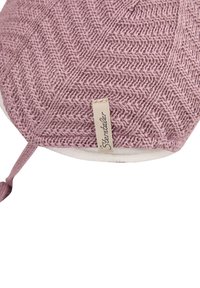 Knitted pink wool round cushion with herringbone pattern, white underside, and a fabric tag, featuring a loop for hanging or carrying.