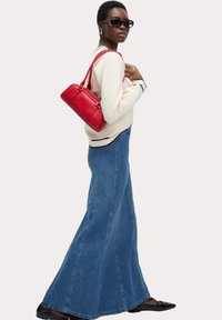 Bla flare-jeanskjol, matchad med en gräddvit topp med svarta detaljer. Accessoarer inkluderar en röd handväska och svarta ballerinas. Solglasögon fulländar looken.