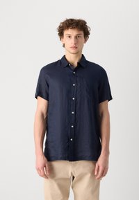 Korte mouwen, marineblauwe linnen shirt met een button-down kraag, voorzakken en een gestructureerde afwerking, gecombineerd met lichtbeige broek.
