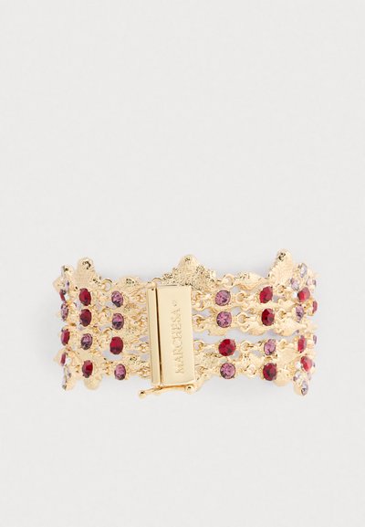 Gouden armband met een gelaagd ontwerp, versierd met rode en paarse stenen, beveiligd met een sluiting gemarkeerd "Marchesa."