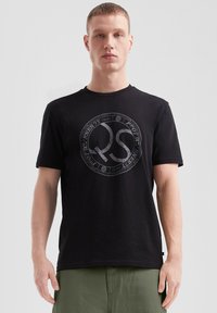 Mustmust värvi t-särk ümmarguse kaeluse ja lühikeste käistega. Keskel on suur hall �ümmargune logo.