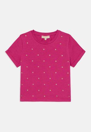 Camiseta de manga corta fucsia hecha de algodón, con acentos de ojales plateados espaciados uniformemente en el frente, y un cuello redondo.