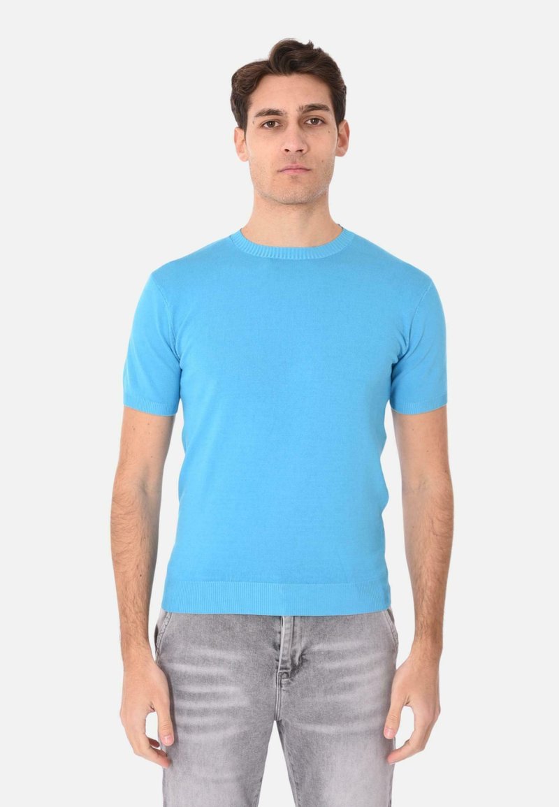 Maglione a maniche corte con collo rotondo di un vivace blu, realizzato in tessuto morbido. Presenta un collo e una fascia in costina, abbinato a jeans grigio chiaro.