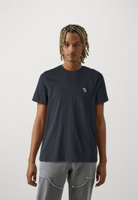 Marineblaue Baumwoll-T-Shirt mit kurzen Ärmeln, Rundhalsausschnitt und einem kleinen weißen gestickten Design auf der Brust.
