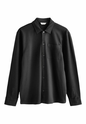 Schwarzes Langarmhemd aus weichem Stoff. Mit spitzem Kragen, Brusttasche und Knopfverschluss mit schwarzen Knöpfen.