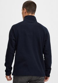Donkerblauwe fleece pullover met een hoge kraag, lange raglanmouwen en een gestructureerd oppervlak. Eenvoudig, geen zichtbare logo's of patronen.