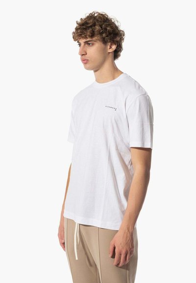 T-shirt bianco in cotone con maniche corte e scollatura tonda. Presenta un piccolo logo nero sul petto sinistro. Vestibilità casual e rilassata.