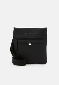 Black leather crossbody bag with pebbled texture, adjustable strap, front zipper pocket, and logo embossed at the top.