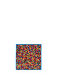 Bufanda floral multicolor con un borde azul. Presenta un patrón de varias rosas en rojo, naranja, amarillo y verde sobre un fondo vívido.