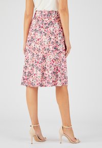 Falda midi floral en rosa, con patrones de hojas negras y naranjas, con una cintura ajustada y un dobladillo acampanado para una silueta fluida.