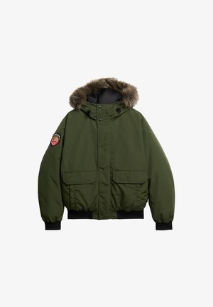 Grøn hætteparka med pelsdetaljer, der har to forlommer, elastiske manchetter og lynlås, lavet af vejrbestandigt stof.