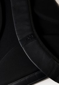 Zaino nero con accenti in pelle liscia, design elegante, trama sottile e un'etichetta del logo ben visibile sulla tracolla.