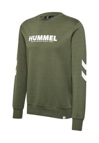 Sudadera verde oliva con el texto "HUMMEL" en blanco. Presenta acentos en chevrón blancos en las mangas. Fabricada con un suave material de mezcla de algodón.