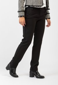 Pantaloni neri su misura in tessuto liscio, con una vestibilità slim e tasche frontali. Abbinati a stivali neri con tacco per un look elegante.