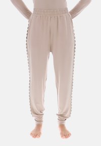 Beige joggebukser med bølget sidentrim, elastisk linning og taperet ben design. Fremstillet af blødt, letvægtsstof.