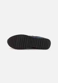 Suola di scarpa in gomma nera con una texture rigata, caratterizzata da una punta arrotondata e scanalature orizzontali per una migliore aderenza.