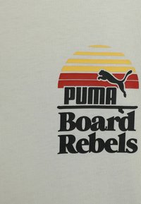 Textil blanco con un gráfico en capas en amarillo, naranja y rojo, acompañado del texto negro "PUMA Board Rebels" y la silueta de un puma negro saltando.