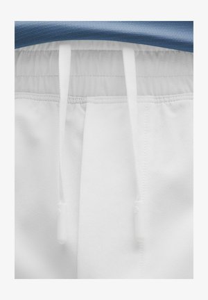 Bílé joggingové kalhoty s elastickým pasem, včetně modrého textilního topu. Bílé šňůrky s plastovými koncovkami pro nastavení. Měkká textura.