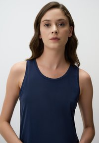 Top senza maniche di colore blu navy con scollatura rotonda, realizzato in tessuto morbido. Design semplice senza fantasie o decorazioni.