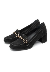 Mocasines de ante negro con un tacón grueso, acento de cadena de oro y costuras blancas contrastantes. Interior suave y suela texturizada.