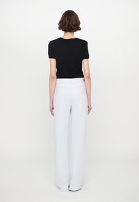Black short-sleeve t-shirt paired with light gray wide-leg pants featuring a smooth texture and a high waistband. Red accent tag visible.