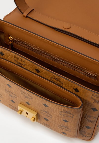 Sac à main en cuir fauve avec un extérieur texturé, une fermeture métallique, plusieurs compartiments intérieurs, et un motif de logo discret.