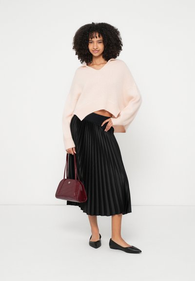 Pull court rose clair, jupe midi plissée noire, ballerines noires et sac à main bordeaux avec des détails géométriques. Textures lisses et design moderne.