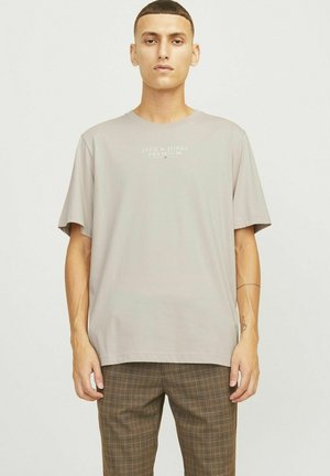 Camiseta de manga corta gris claro con cuello redondo; presenta el texto "Jack & Jones Premium" impreso en la parte frontal. Textura de tela suave y lisa.